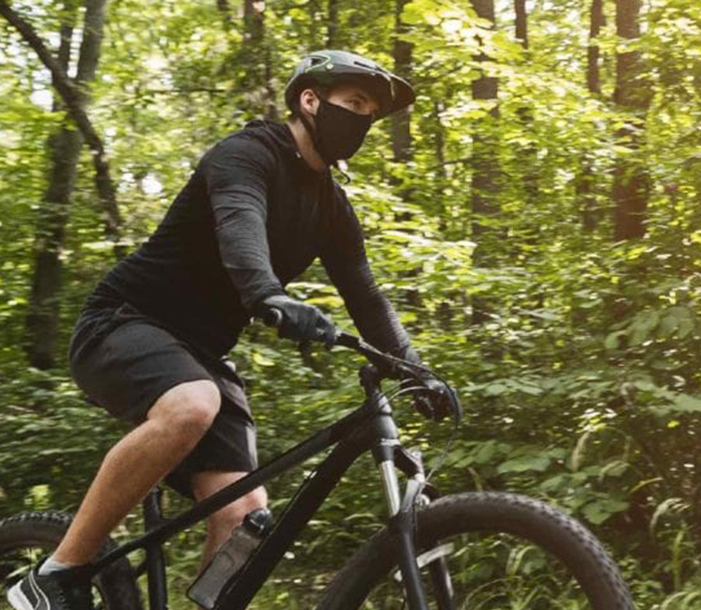 NAROO F.U Plus - Man cycling in a forest wearing a black FU+copper sports mask for pollen and pollution v2